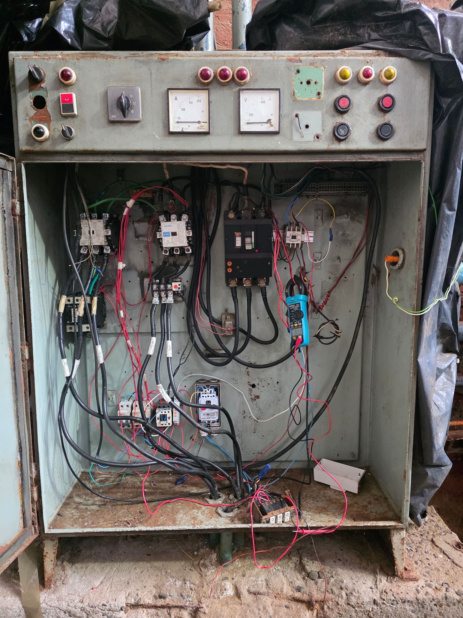 Tablero eléctrico del compresor en revisión con pinza amperimétrica