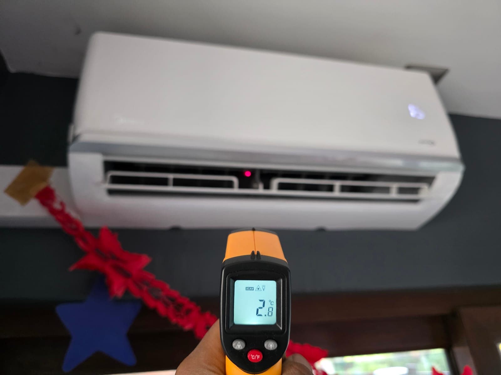Pirómetro midiendo 2,8 °C en la salida de un aire acondicionado después de su mantención